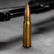 Single bullet standing upright with blurred dark firearm Single bullet standing upright with blurred dark firearm - PhotoDune Item for Sale