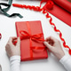 Woman tying decorative bow on paper wrapped gift during celebration preparation Woman tying decorative bow on paper wrapped gift during celebration preparation - PhotoDune Item for Sale