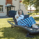 A blonde woman with a laptop works in the garden on a sun lounger, home office concept. A blonde woman with a laptop works in the garden on a sun lounger, home office concept. - PhotoDune Item for Sale