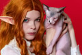 Portrait of young female cosplayer elf showing purebred Sphinx kitten with blue eyes Portrait of young female cosplayer elf showing purebred Sphinx kitten with blue eyes - PhotoDune Item for Sale