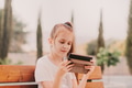 Little girl preteen holding tablet gadget and taking in video chat. female sitting on bench Little girl preteen holding tablet gadget and taking in video chat. female sitting on bench - PhotoDune Item for Sale