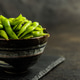 Green edamame pods. Fresh soybeans in bowl on black table. Green edamame pods. Fresh soybeans in bowl on black table. - PhotoDune Item for Sale