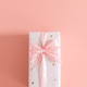 One gift box with a bow on a pink background. One gift box with a bow on a pink background. - PhotoDune Item for Sale