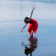 Woman in a red dress gracefully dances on a tranquil lake with rippling water reflections. WA, USA Woman in a red dress gracefully dances on a tranquil lake with rippling water reflections. WA, USA - PhotoDune Item for Sale