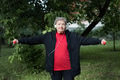 Smiling elderly woman is doing exercises with dumbbells outdoors in the yard. Active old ages Smiling elderly woman is doing exercises with dumbbells outdoors in the yard. Active old ages - PhotoDune Item for Sale