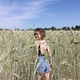 A young girl in shorts and a top with an open back stands in a wheat field. Summertime. Hot days A young girl in shorts and a top with an open back stands in a wheat field. Summertime. Hot days - PhotoDune Item for Sale