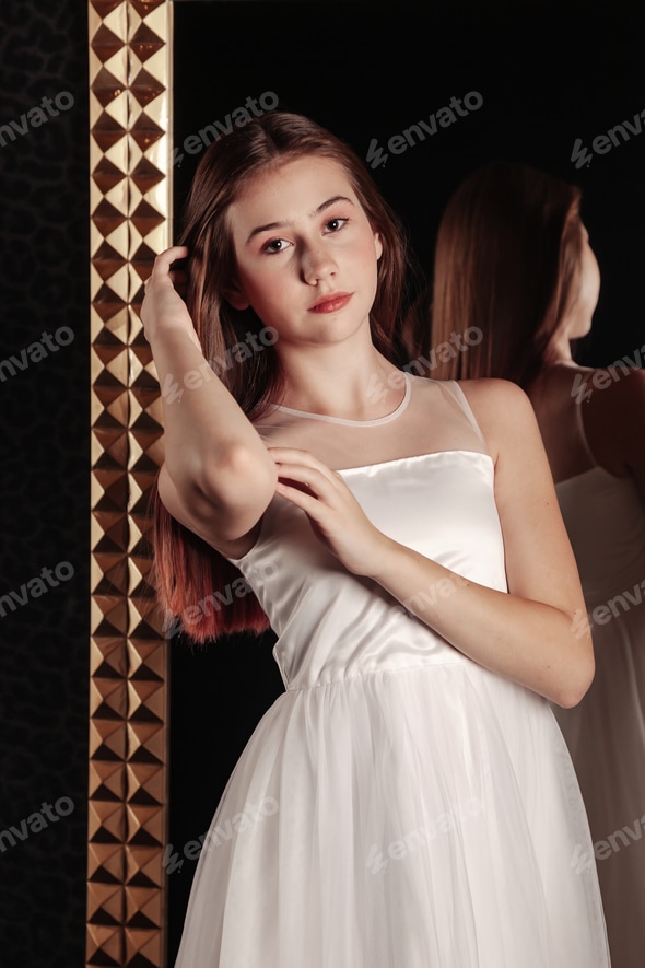 Portrait cute teen girl in an elegant white dress at mirror in dark stylish interior of living room Stock Photo by AlexVog Portrait cute teen girl in an elegant white dress at mirror in dark stylish interior of living room Stock Photo by AlexVog