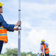 Two civil engineers wearing helmets and reflective vests perform land surveying Two civil engineers wearing helmets and reflective vests perform land surveying - PhotoDune Item for Sale