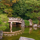 Stone bridge over pond in Japanese garden surrounded by greenery Stone bridge over pond in Japanese garden surrounded by greenery - PhotoDune Item for Sale