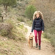 Curly and blonde hair, mountaineer woman and her dog walking through the mountains. Curly and blonde hair, mountaineer woman and her dog walking through the mountains. - PhotoDune Item for Sale