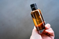 Hand holding a amber glass bottles on grey background Hand holding a amber glass bottles on grey background - PhotoDune Item for Sale