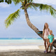 Two young girls standing by a palm tree on a tropical beach Two young girls standing by a palm tree on a tropical beach - PhotoDune Item for Sale