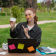 Student, freelancer sitting, holding card, pointing by finger in park. Student, freelancer sitting, holding card, pointing by finger in park. - PhotoDune Item for Sale