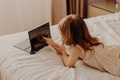 Toddler girl lying in bedroom, using laptop tablet pad gadget, people from behind Toddler girl lying in bedroom, using laptop tablet pad gadget, people from behind - PhotoDune Item for Sale