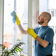 doing spring cleaning. a man in yellow rubber gloves washes a window at home. cleaning the house. doing spring cleaning. a man in yellow rubber gloves washes a window at home. cleaning the house. - PhotoDune Item for Sale