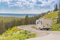 Camper Driving Down Road in The Beautiful Countryside Among Pine Trees and Flowers. Camper Driving Down Road in The Beautiful Countryside Among Pine Trees and Flowers. - PhotoDune Item for Sale