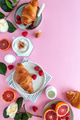 Flat lay of a breakfast scene with croissants, fruit, cappuccino on pink background Flat lay of a breakfast scene with croissants, fruit, cappuccino on pink background - PhotoDune Item for Sale