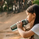 Little girl with dark hair drinking water from bottle sitting outdoor. Little girl with dark hair drinking water from bottle sitting outdoor. - PhotoDune Item for Sale