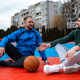 Two men sit on a basketball court discussing their game and enjoying the afternoon sunlight Two men sit on a basketball court discussing their game and enjoying the afternoon sunlight - PhotoDune Item for Sale
