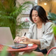 Pretty asian businesswoman student holding pen writing in book over a laptop at table in garden cafe Pretty asian businesswoman student holding pen writing in book over a laptop at table in garden cafe - PhotoDune Item for Sale