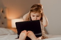 Toddler girl sitting in bedroom, using laptop tablet pad gadget, watching with focused face Toddler girl sitting in bedroom, using laptop tablet pad gadget, watching with focused face - PhotoDune Item for Sale