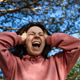 Outdoors angled bottom view of a young woman who screams and covers her snakes with her hands. Outdoors angled bottom view of a young woman who screams and covers her snakes with her hands. - PhotoDune Item for Sale