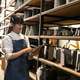 Young woman in apron scanning items on tablet in a storage warehouse Young woman in apron scanning items on tablet in a storage warehouse - PhotoDune Item for Sale