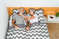 Happy senior couple laughing together while lying in bed below blankets Happy senior couple laughing together while lying in bed below blankets - PhotoDune Item for Sale