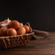Rustic woven basket filled with fresh brown eggs, placed on wooden background with white feather Rustic woven basket filled with fresh brown eggs, placed on wooden background with white feather - PhotoDune Item for Sale