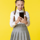 Schoolgirl in uniform with braided hair using smartphone on bright yellow background Schoolgirl in uniform with braided hair using smartphone on bright yellow background - PhotoDune Item for Sale