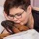 Young woman with short brown hair hugging her black and brown dog on a cozy white bed in a bedroom Young woman with short brown hair hugging her black and brown dog on a cozy white bed in a bedroom - PhotoDune Item for Sale