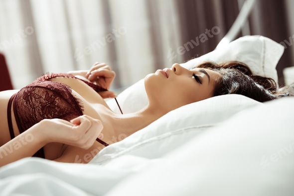 gorgeous seductive woman in sexy bra lying on bed at home Stock Photo by LightFieldStudios gorgeous seductive woman in sexy bra lying on bed at home Stock Photo by LightFieldStudios