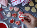 Woman holding a heart shaped cookie with the word love and flat lay of baked cookies in background Woman holding a heart shaped cookie with the word love and flat lay of baked cookies in background - PhotoDune Item for Sale