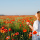 Young woman smelling poppy flower enjoying summer in poppy field Young woman smelling poppy flower enjoying summer in poppy field - PhotoDune Item for Sale