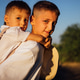 Two boys, one carrying the other on his back, smiling joyfully in a sunny outdoor Two boys, one carrying the other on his back, smiling joyfully in a sunny outdoor - PhotoDune Item for Sale