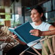 A Smiling Woman Enjoys Reading a Book while Relaxing in a Cozy and Comfortable Cafe A Smiling Woman Enjoys Reading a Book while Relaxing in a Cozy and Comfortable Cafe - PhotoDune Item for Sale