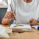 Woman painting in a small home craft area with organized tools Woman painting in a small home craft area with organized tools - PhotoDune Item for Sale