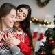 Smiling brunette woman hugging girlfriend during christmas celebration at home Smiling brunette woman hugging girlfriend during christmas celebration at home - PhotoDune Item for Sale