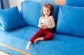 Cute toddler girl wear casual clothes sitting on blue coach in domestic room, holding smartphone Cute toddler girl wear casual clothes sitting on blue coach in domestic room, holding smartphone - PhotoDune Item for Sale