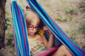 Cute little girl in eyeglasses laying in a hammock and using tablet. Cute little girl in eyeglasses laying in a hammock and using tablet. - PhotoDune Item for Sale