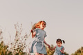 Two little girls holding each other hands and walking outdoors. Two little girls holding each other hands and walking outdoors. - PhotoDune Item for Sale