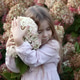 Little Girl Embracing White Hydrangea Flowers with Tenderness and Wonder in a Lush Garden Setting. Little Girl Embracing White Hydrangea Flowers with Tenderness and Wonder in a Lush Garden Setting. - PhotoDune Item for Sale