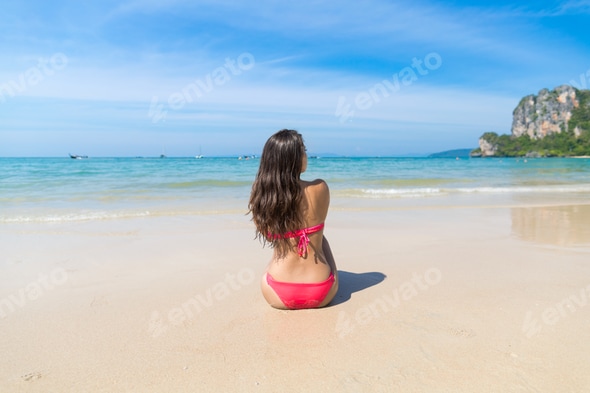 Attractive Young Caucasian Woman In Swimsuit Sitting On Beach Back