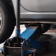 Blue hydraulic floor jack lifting a car for maintenance and repair. Blue hydraulic floor jack lifting a car for maintenance and repair. - PhotoDune Item for Sale