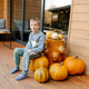 Boy sitting on pumpkin decorating autumn porch Boy sitting on pumpkin decorating autumn porch - PhotoDune Item for Sale