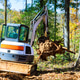 Excavator removing debris in forested area during autumn season Excavator removing debris in forested area during autumn season - PhotoDune Item for Sale