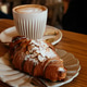 Delicious almond croissant with a latte in a cozy cafe setting Delicious almond croissant with a latte in a cozy cafe setting - PhotoDune Item for Sale