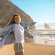 Happy woman standing with arms outstretched on seashore at beach Happy woman standing with arms outstretched on seashore at beach - PhotoDune Item for Sale
