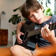Young boy playing an acoustic guitar indoors, focused on pressing strings and fretboard Young boy playing an acoustic guitar indoors, focused on pressing strings and fretboard - PhotoDune Item for Sale