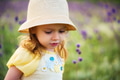Cute serious baby girl in hat looks down outdoors in green field. Child portrait Cute serious baby girl in hat looks down outdoors in green field. Child portrait - PhotoDune Item for Sale